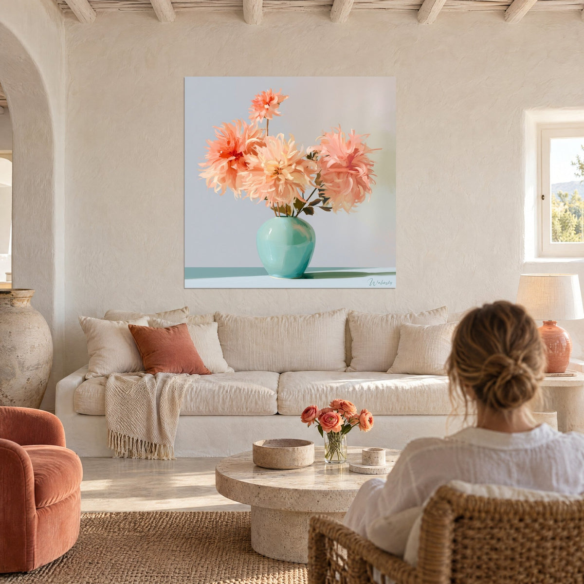 Tableau bouquet de dahlias pêche et corail dans un vase turquoise, fond gris-bleu, au-dessus d'un canapé dans un salon lumineux