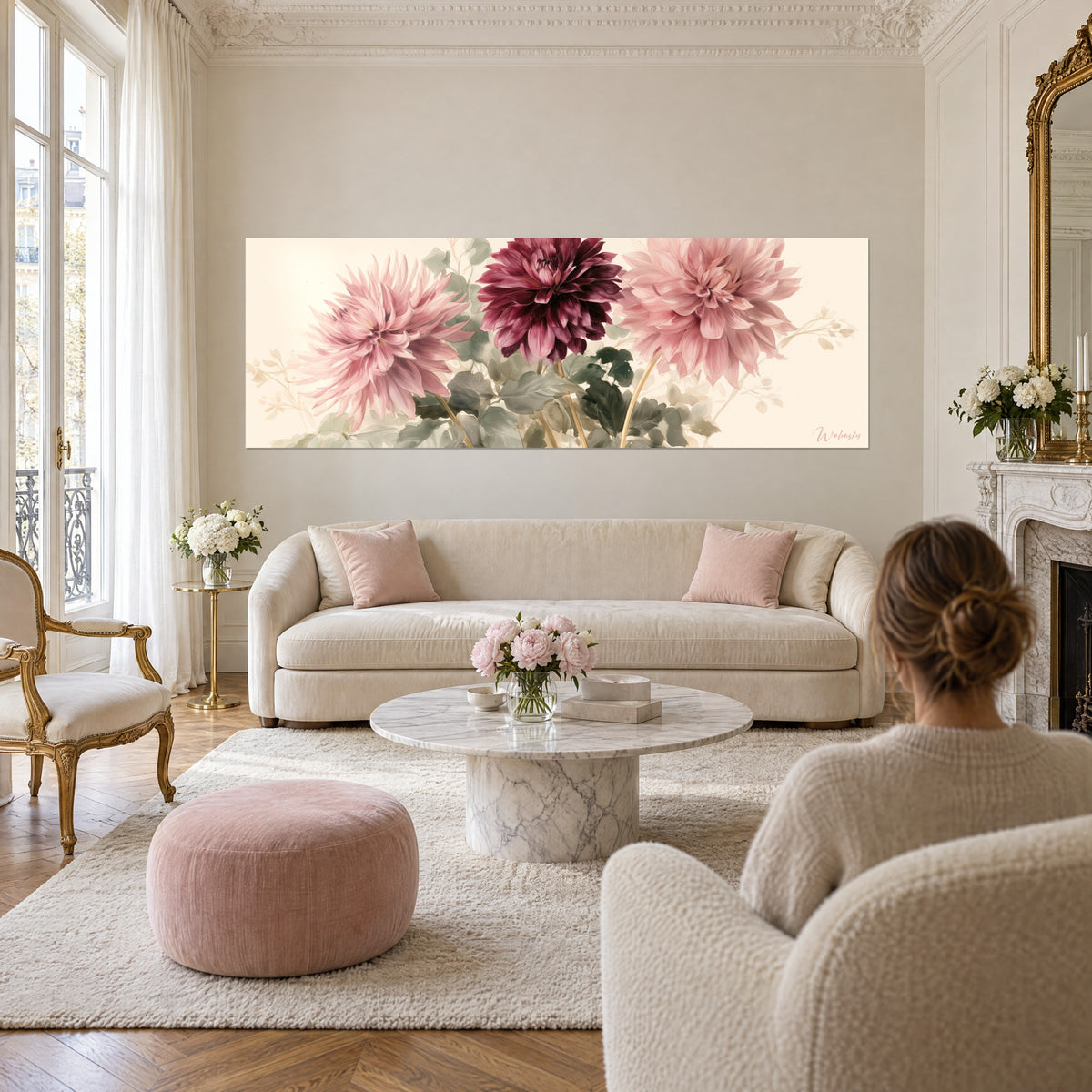 Quadro con tre dalie rosa cipria e bordeaux su fondo crema, fogliame verde-grigio, sopra un divano in un soggiorno luminoso