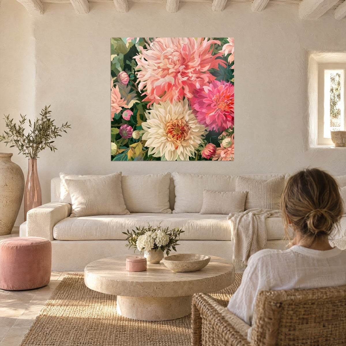 Tableau dahlias crème et corail en peinture épaisse, une femme de dos le regarde, au-dessus d'un canapé dans un salon lumineux