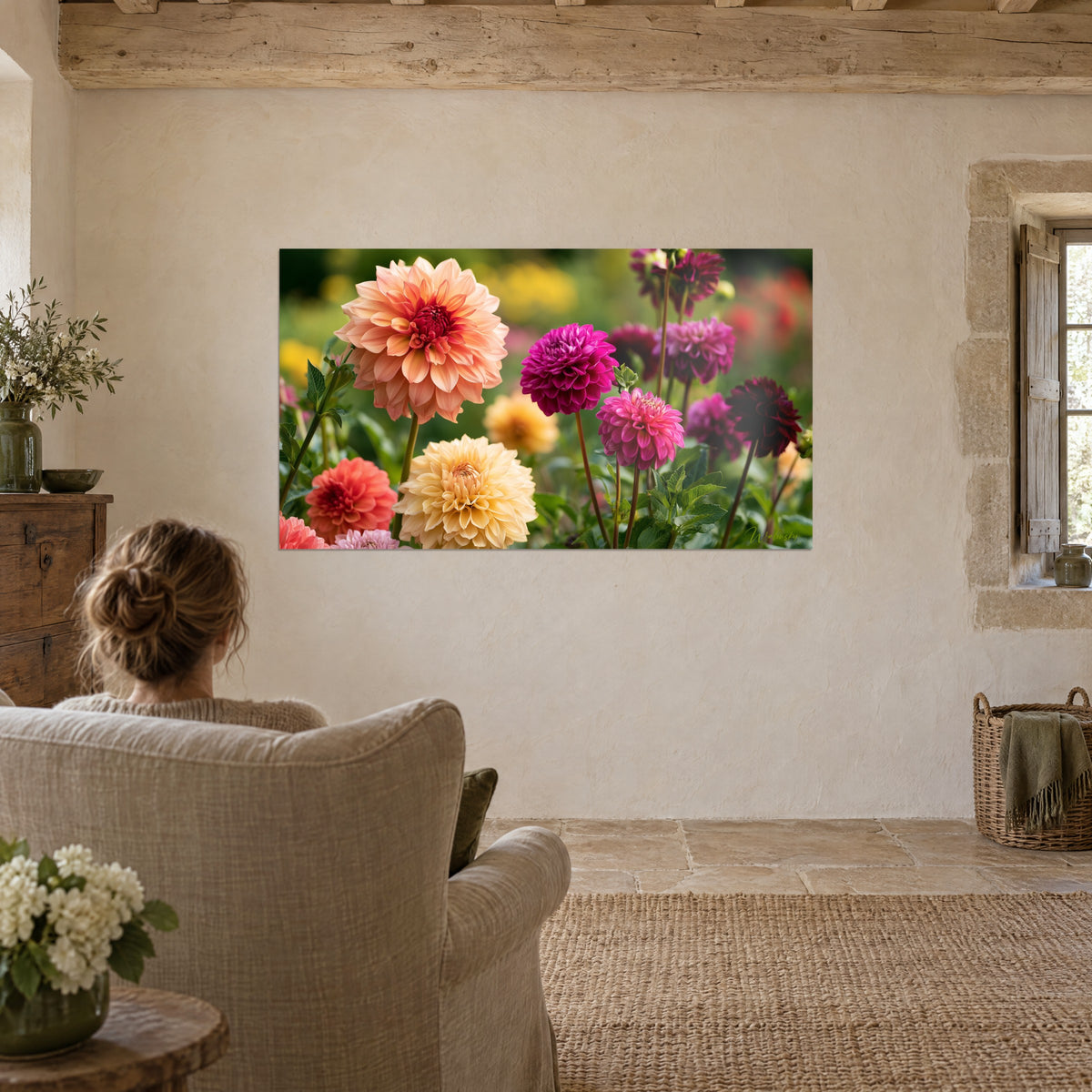 Wall art of giant dahlias with a gradient from peach to magenta pink, blurred golden-green background, facing a beige linen armchair in a vaulted living room