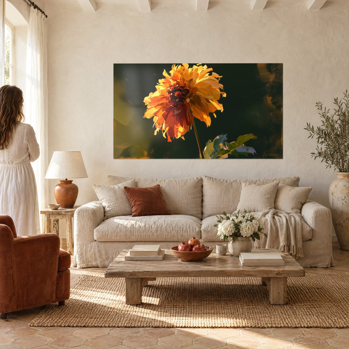 Quadro dalia arancione dai petali dorati su sfondo verde scuro, donna di spalle, sopra un divano in un soggiorno luminoso