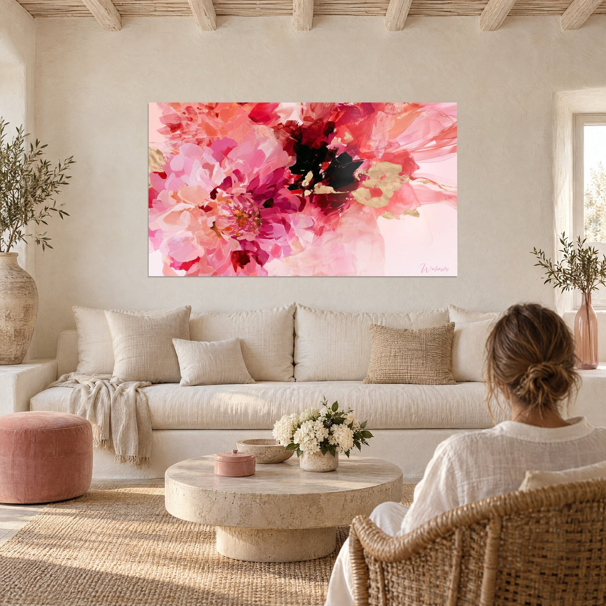 Tableau pivoine rose et fuchsia aux touches noires, cœur safran doré, avec femme de dos, au-dessus d'un canapé dans un salon lumineux