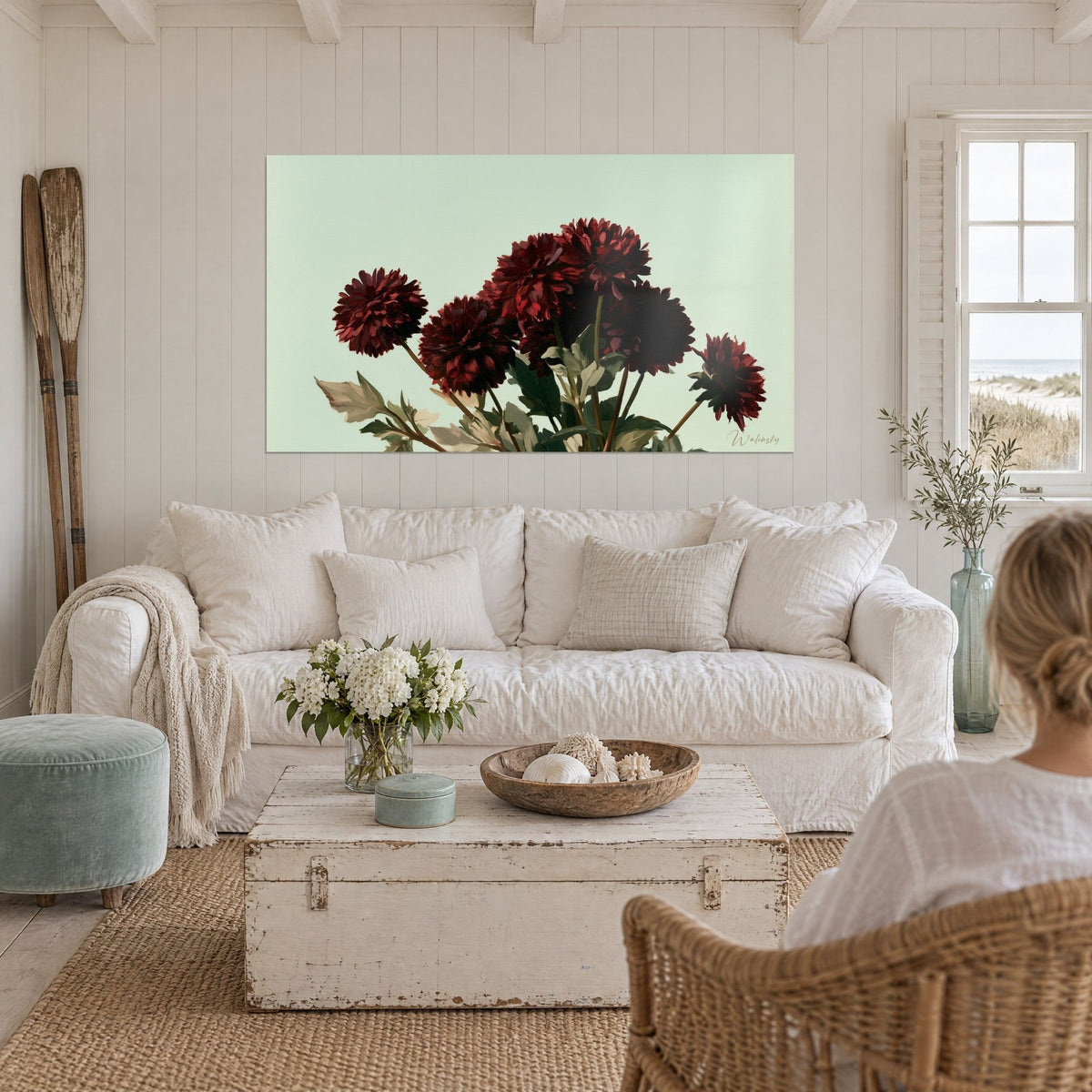 Tableau dahlias pompons bordeaux sur fond vert amande, feuilles grises, au-dessus d'un canapé dans un salon lumineux