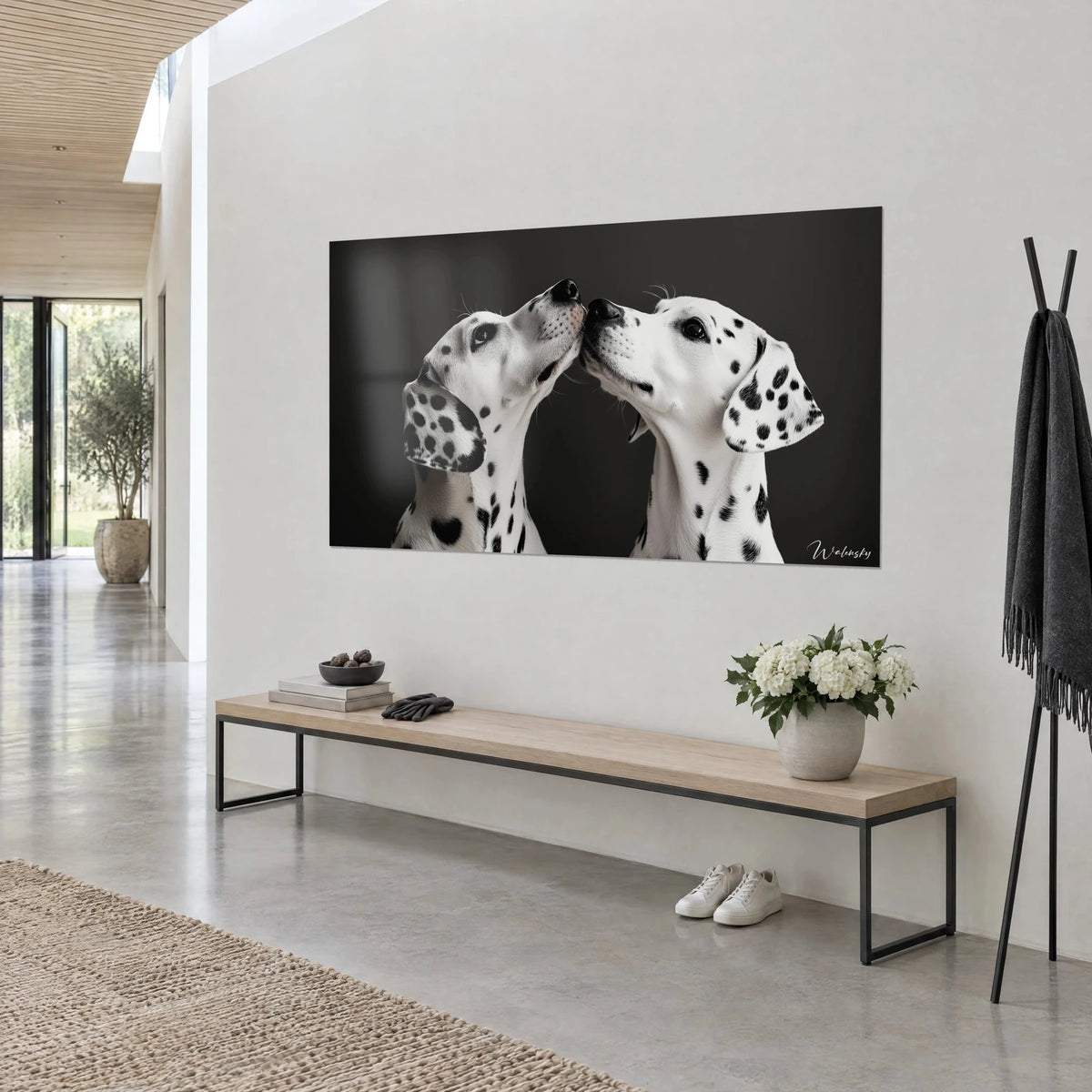 Wall art pair of spotted dogs nuzzling noses, white coat and black spots on a dark grey background, light wall and wooden bench
