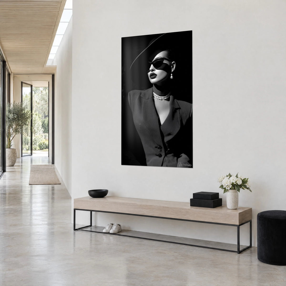 Cuadro retrato de moda en blanco y negro, labios oscuros, pendiente de perla marfil, fondo negro profundo, pared blanca y banco de madera