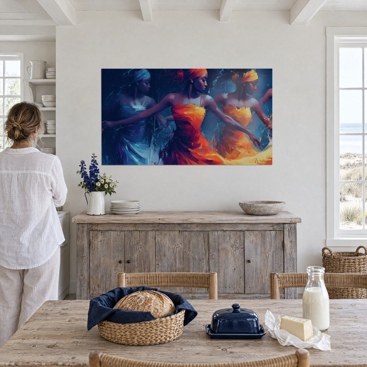 Cuadro de mujeres bailando en círculo, pañuelos naranja intenso, telas azul cobalto salpicadas de blanco, frente a un comedor junto al mar