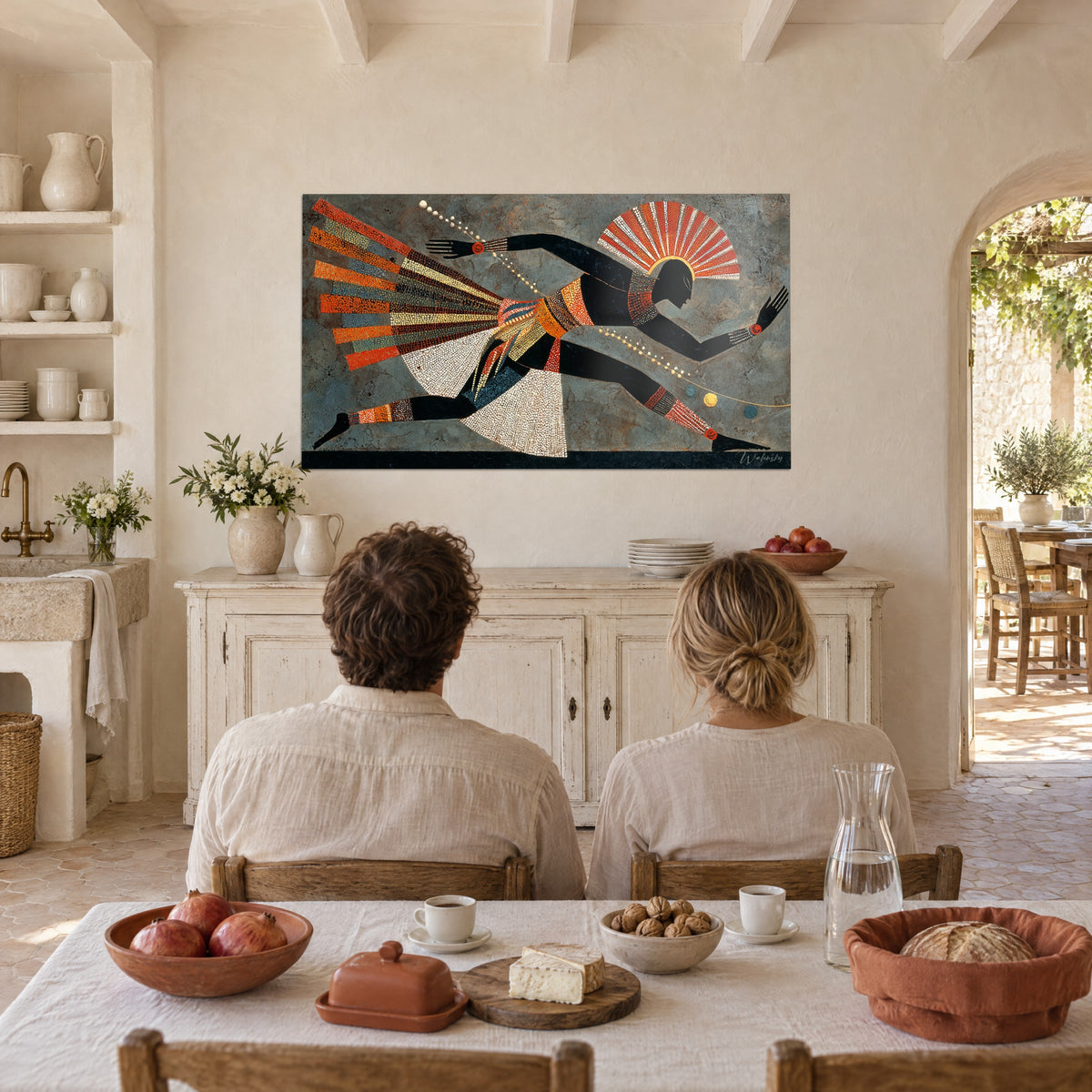 Wall art of a slender tribal figure in a dot mosaic, ochre and vivid red on grey background, hung in a Provençal dining nook