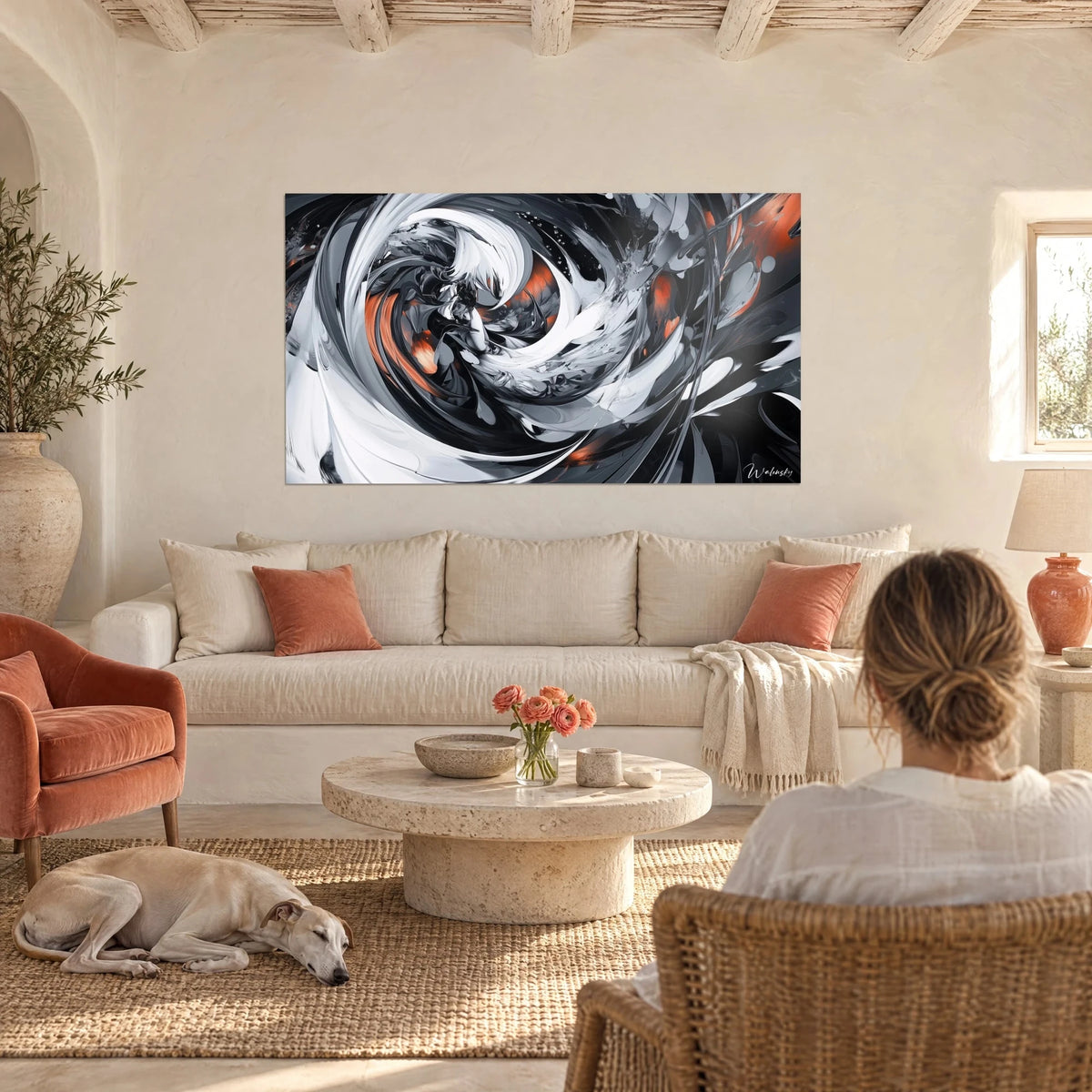 Tableau tourbillon blanc et noir aux éclats orange brûlé, une femme de dos et un lévrier, au-dessus d'un canapé dans un salon lumineux