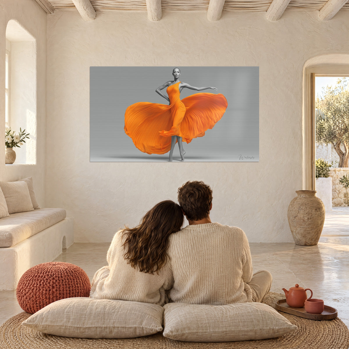 Cuadro bailarina de cabeza rapada, vestido plisado naranja flamante sobre gris perla, contemplada por una pareja de espaldas sentada en cojines en un salón abovedado