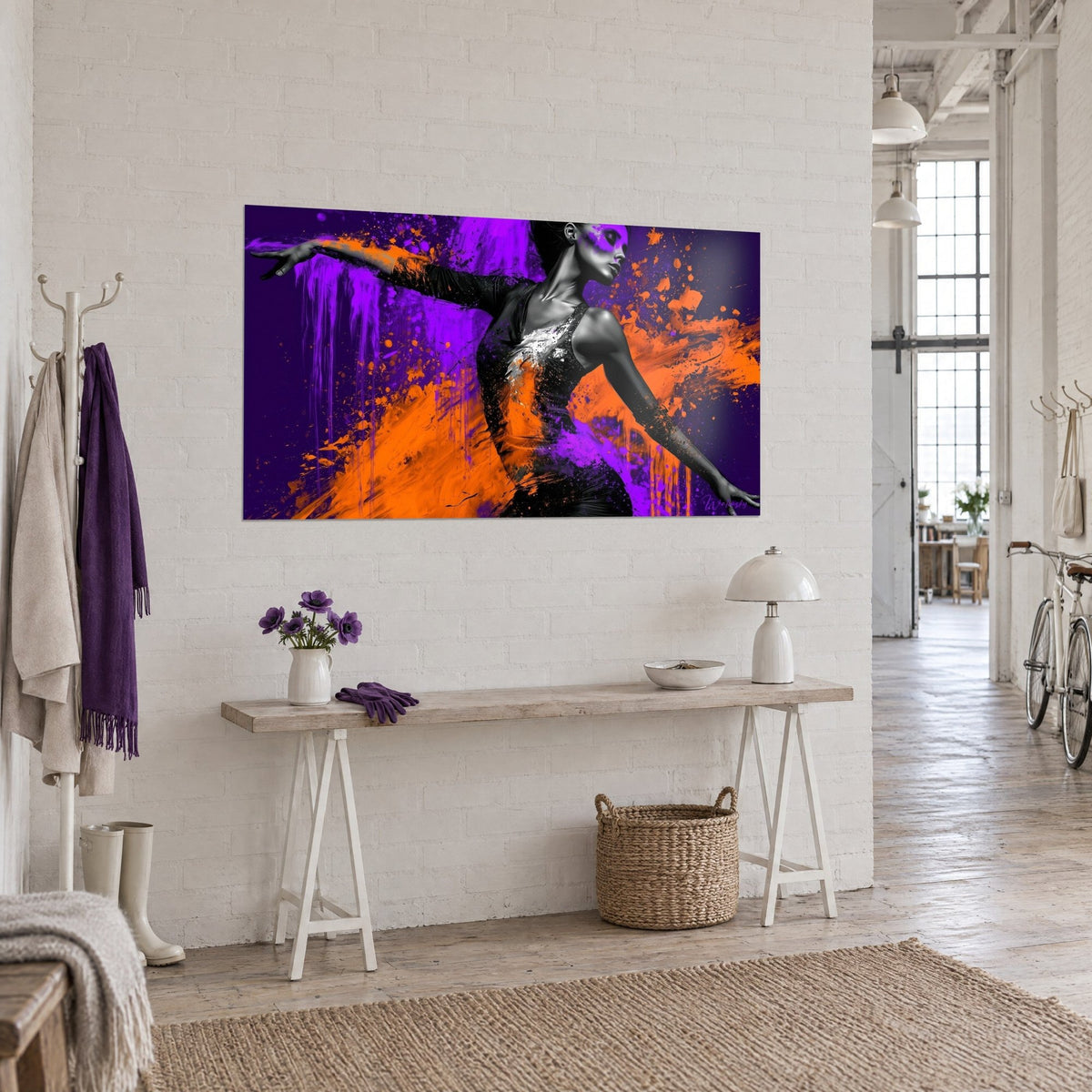 Tableau ballerine en noir et blanc cernée de coulures violettes et d'éclats orange, accroché sur un mur de briques blanches