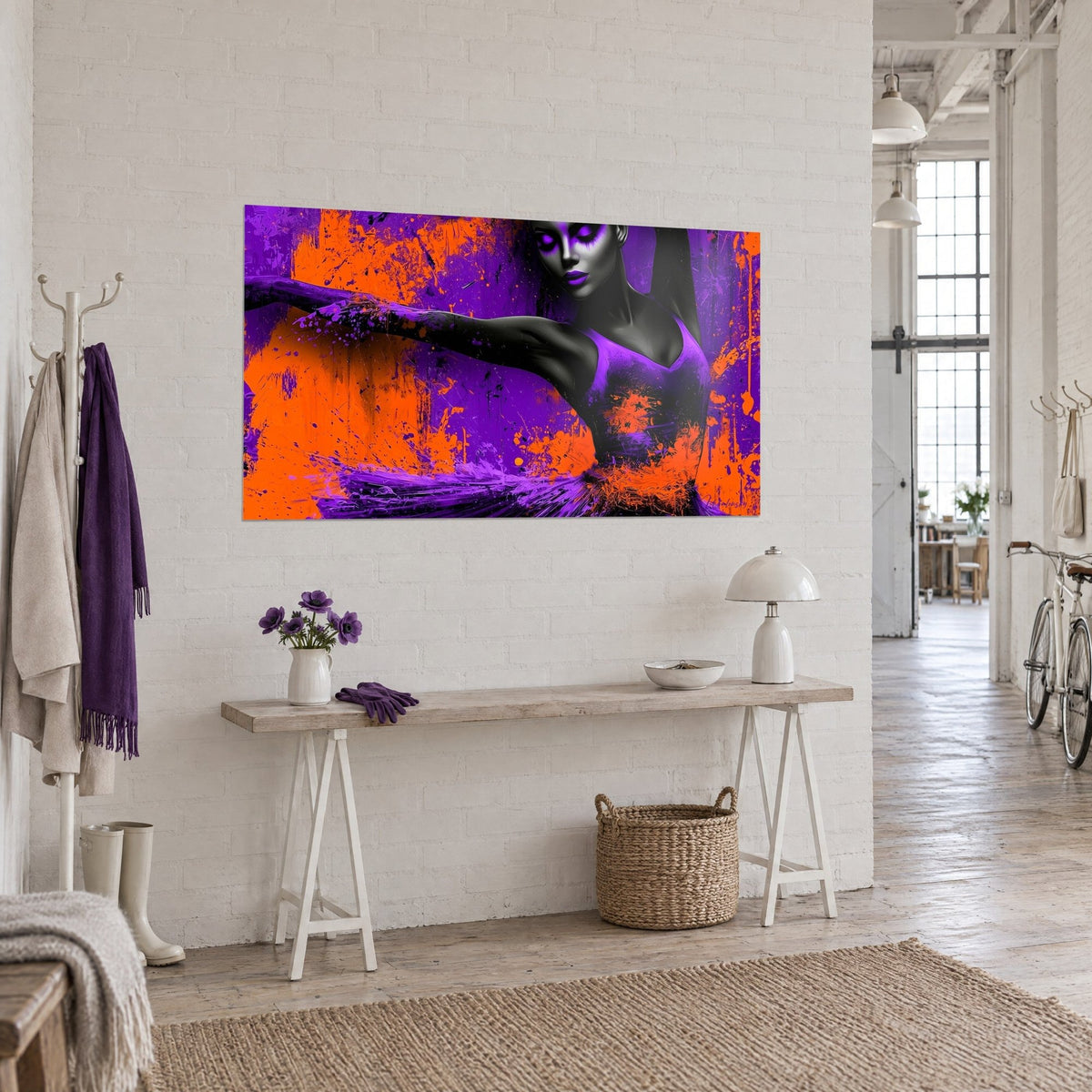 Tableau ballerine stylisée, paupières violettes et fond orange vif, sur un mur blanc au-dessus d'une console en bois clair