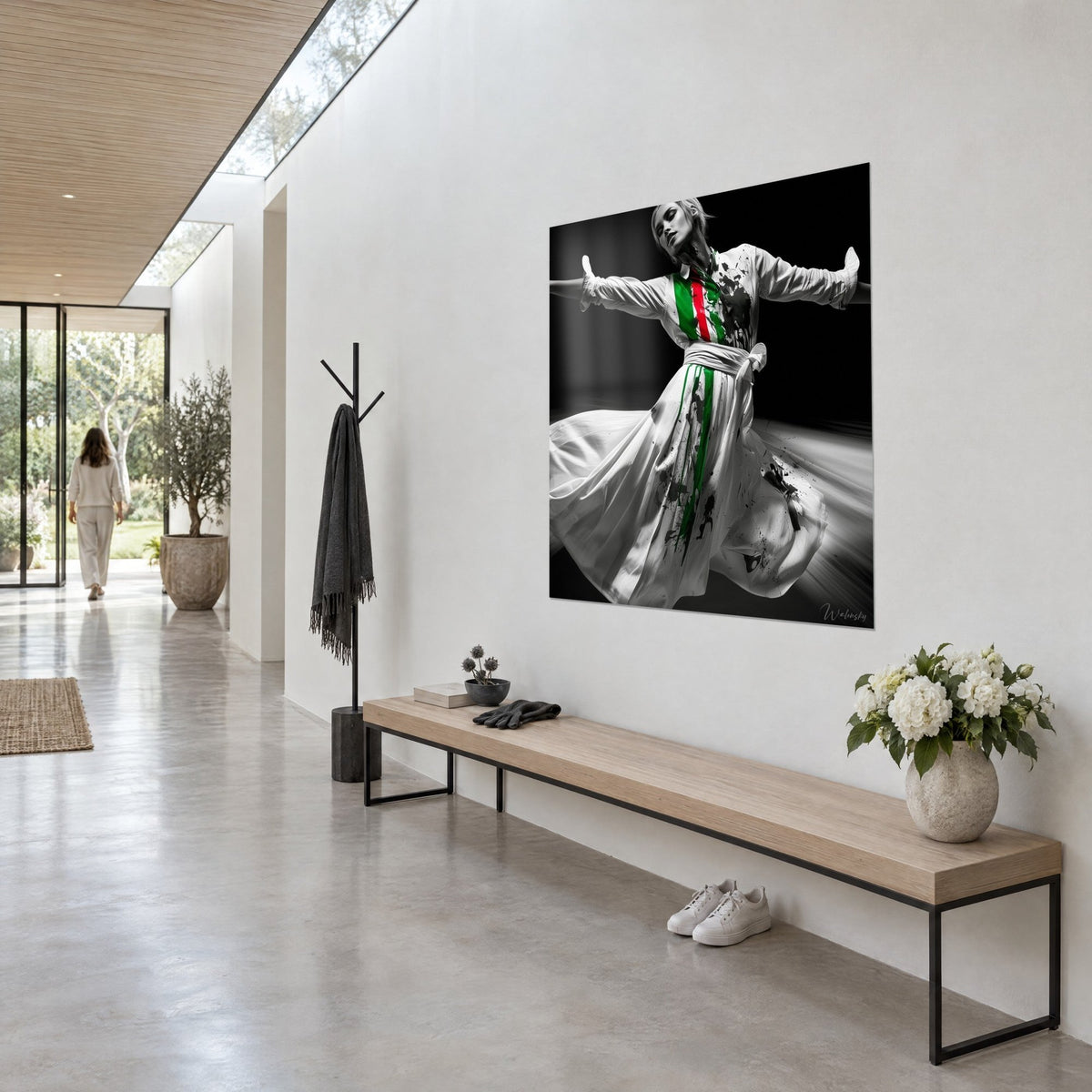 Tableau derviche aux bras en croix, jupe blanche éclaboussée de noir et de vert, dans un couloir de béton clair vu de trois-quarts