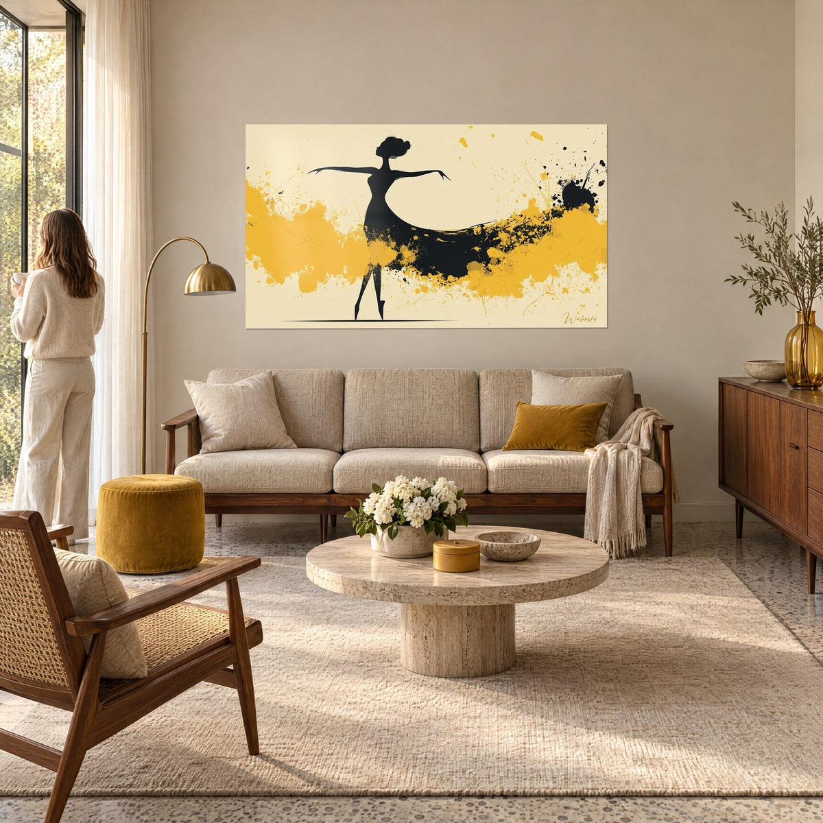 Tableau danseuse en silhouette noire aux bras écartés, éclaboussures jaune moutarde sur fond crème, au-dessus d'un canapé dans un salon lumineux
