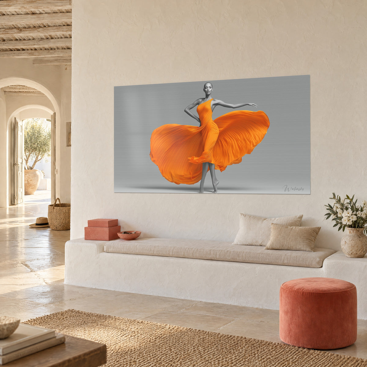 Cuadro vestido naranja desplegado en abanico, silueta gris de cabeza rapada, colgado en una pared crema junto a un banco blanco y un puf terracota
