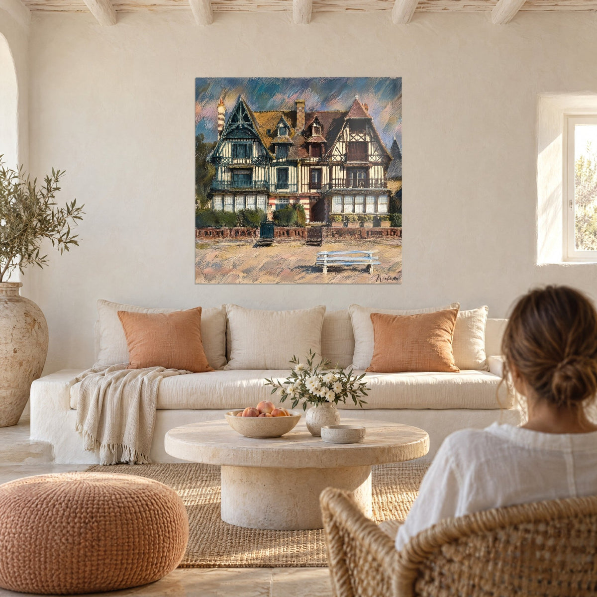 Schilderij Normandische villa met blauw en bruin vakwerk, witte bank op het strand, boven een bank in een lichte woonkamer
