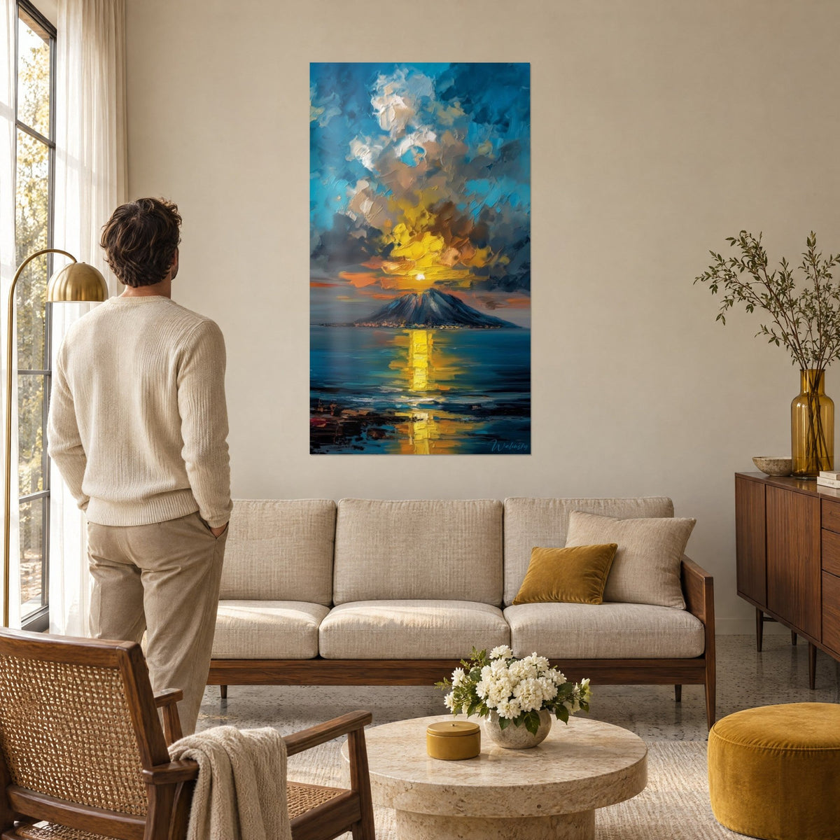 Gemälde Vulkanausbruch unter einer Wolkenwand in Blau und Sonnengelb, goldener Schimmer auf dem Meer, über dem Sofa in einem hellen Wohnzimmer