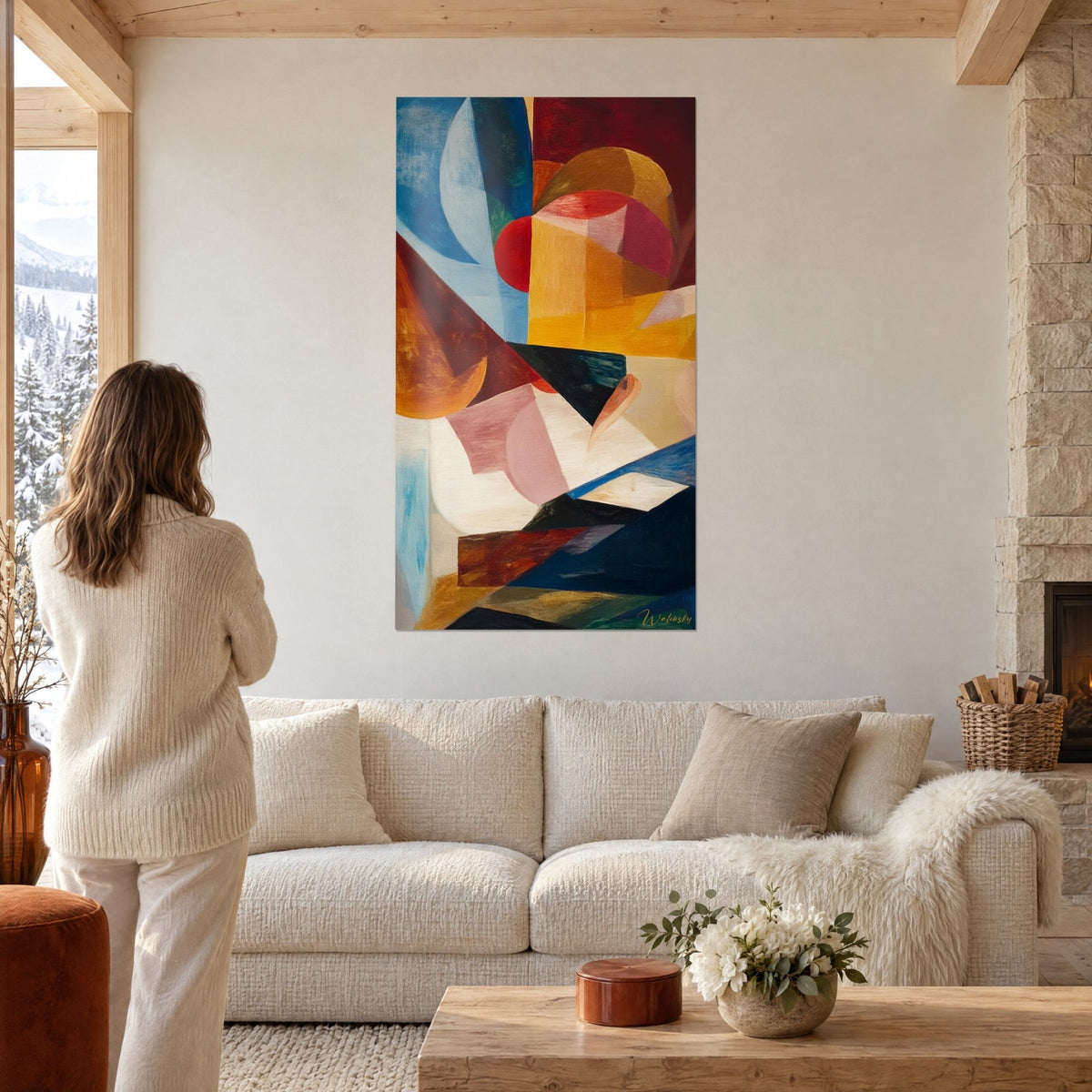Wall art geometric composition in red, yellow and blue, woman seen from behind, hung above a sofa in a bright living room