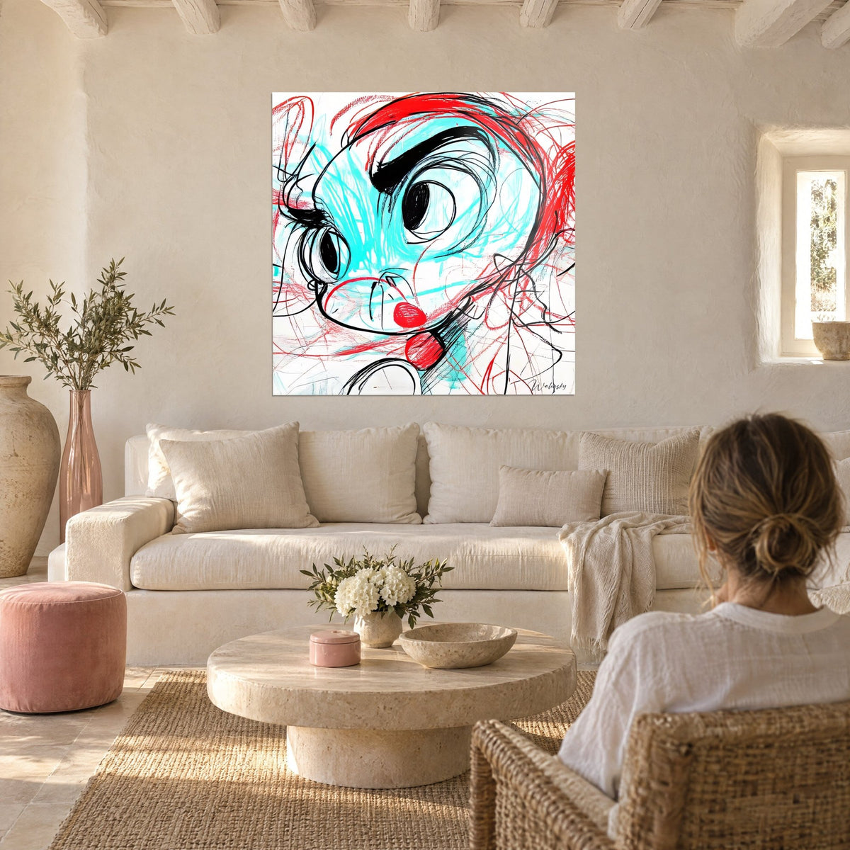 Wall art with an expressive face, round black eyes, turquoise and bright red strokes, above a sofa in a bright living room