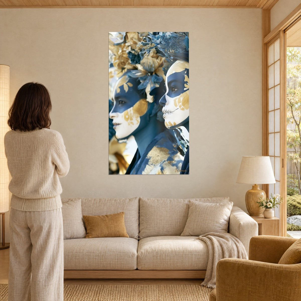 Tableau deux visages peints en bleu nuit et or, couronne de fleurs bleutées, femme de dos, au-dessus d'un canapé dans un salon lumineux