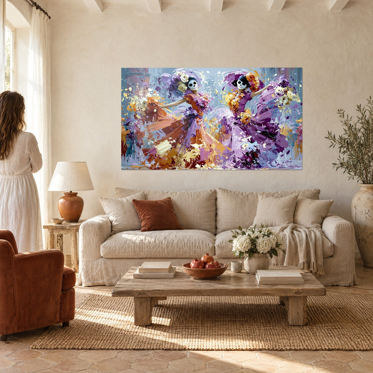 Tableau deux Catrinas en robes orange et violettes, masques de crâne, roses blanches, au-dessus d'un canapé dans un salon lumineux