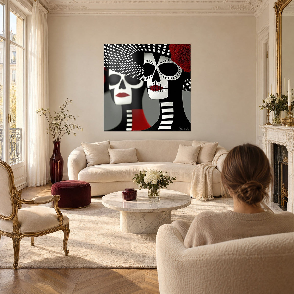 Tableau deux calaveras ivoire aux lèvres écarlates, chapeaux à damier noir et blanc, au-dessus d'un canapé dans un salon lumineux