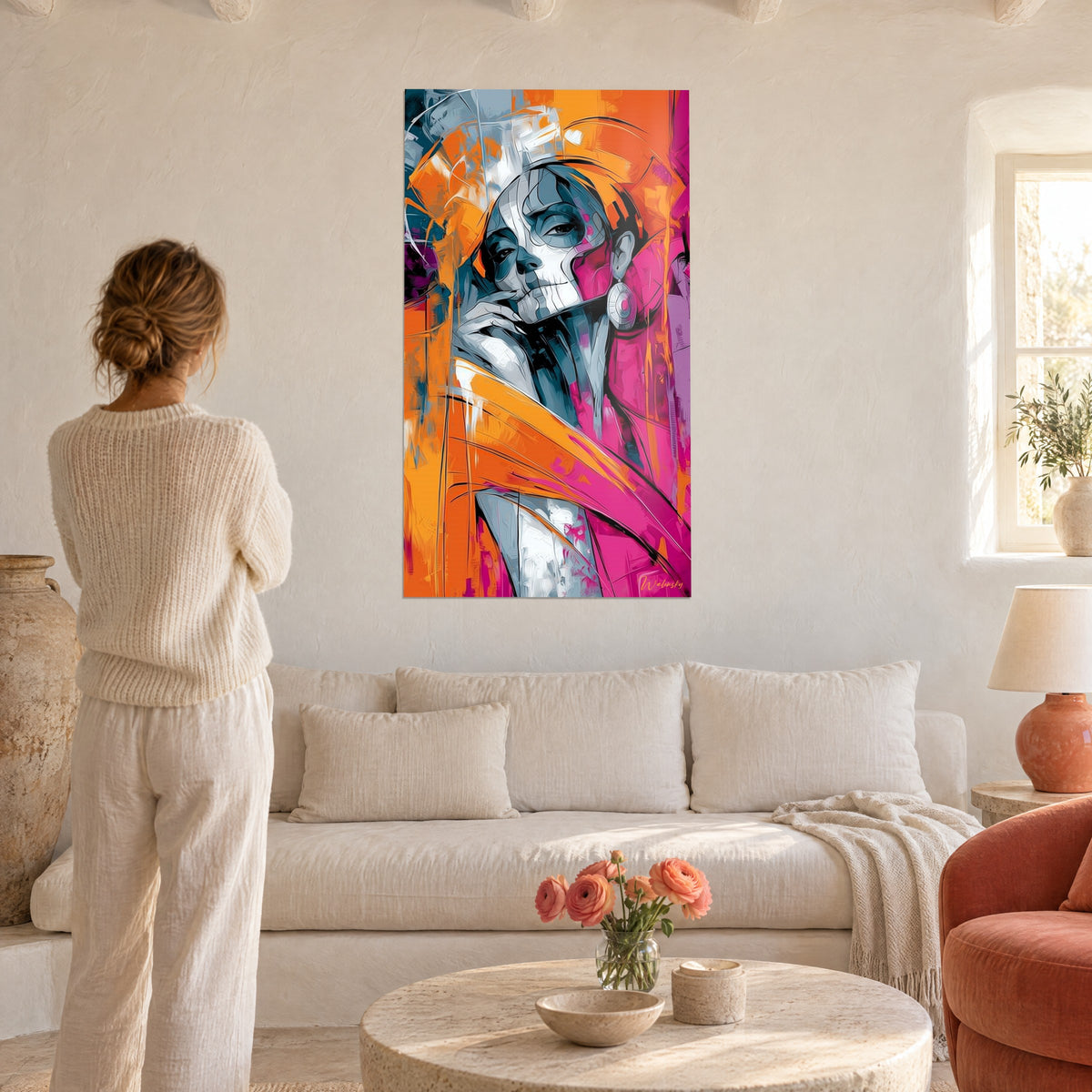 Wall art of an orange and magenta calavera face, hand resting under the chin, a woman seen from behind above a sofa in a bright living room