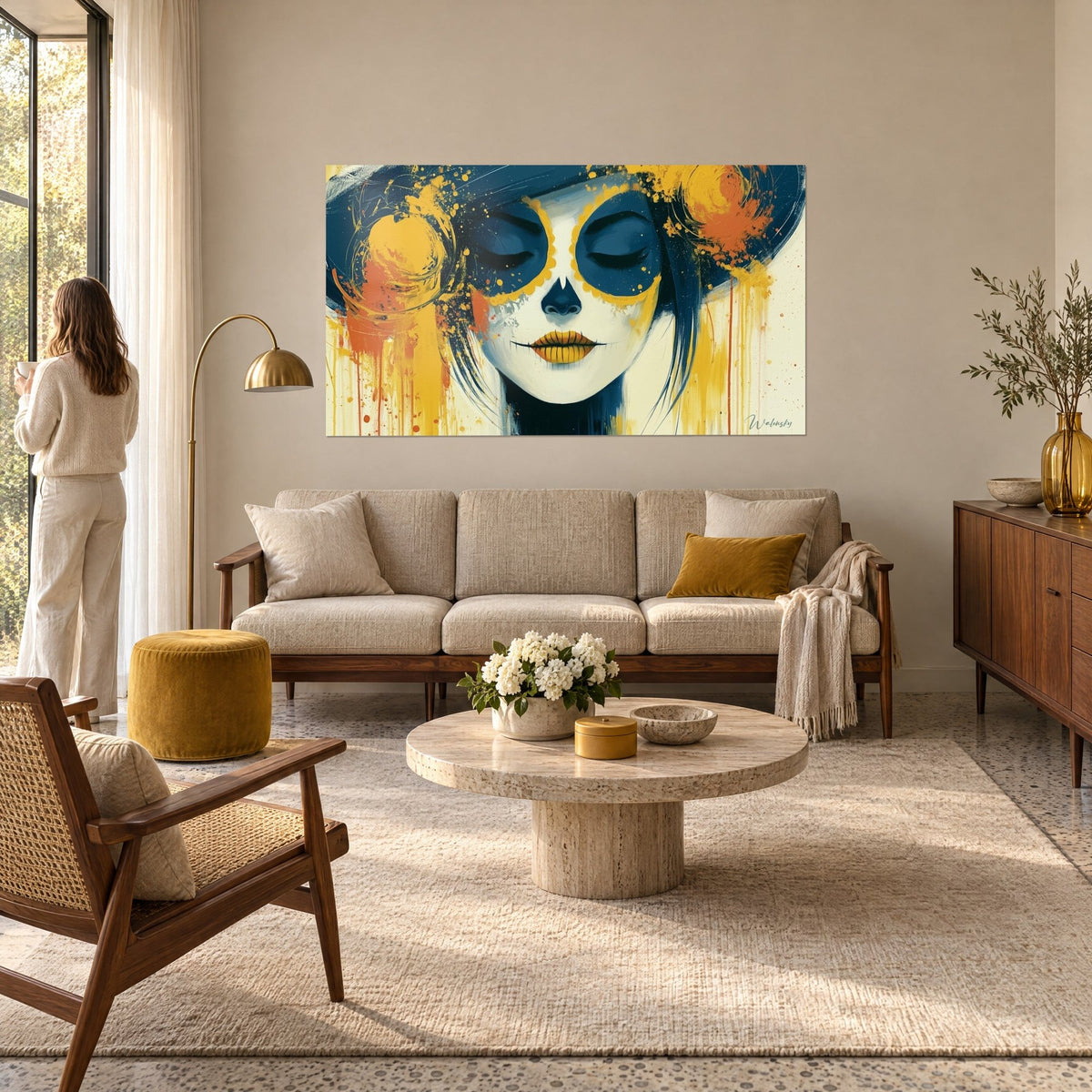 Quadro volto dipinto con gli occhi chiusi dorati, maschera bianca, cappello blu notte e schizzi ocra, sopra un divano in un soggiorno luminoso