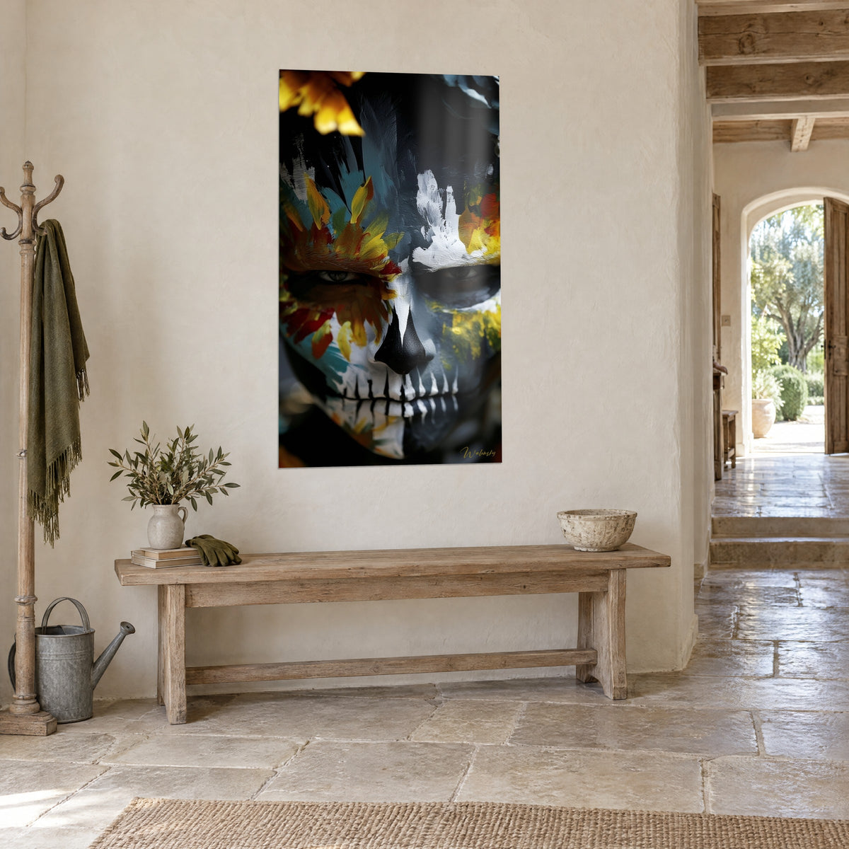 Quadro di volto calavera con zigomi grigi e petali zafferano, sguardo diviso in due metà, appeso in un ingresso in pietra