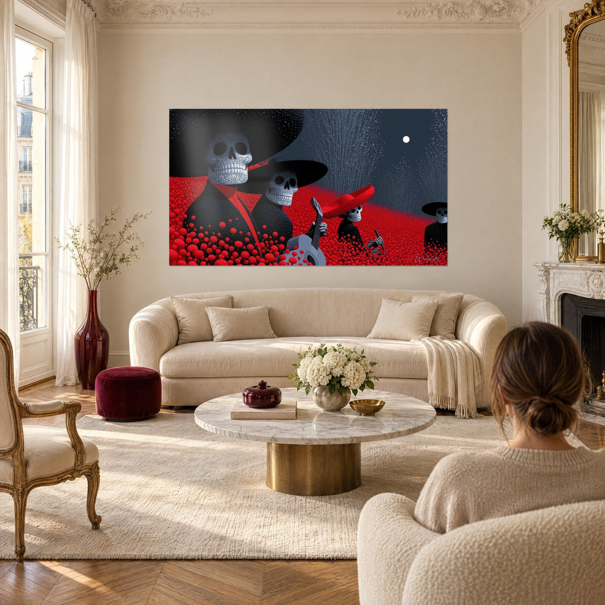 Gemälde Trio aus Mariachi-Skeletten unter schwarzen Sombreros, rotes Blumenfeld und weißer Mond, über einem Sofa in einem hellen Wohnzimmer