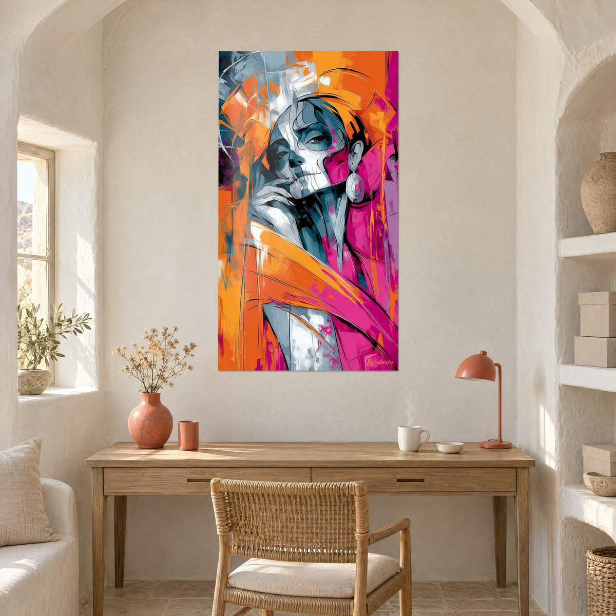 Wall art of a Catrina with graphic bluish-grey features, orange and magenta brushstrokes, hung above a light wood desk and a terracotta lamp