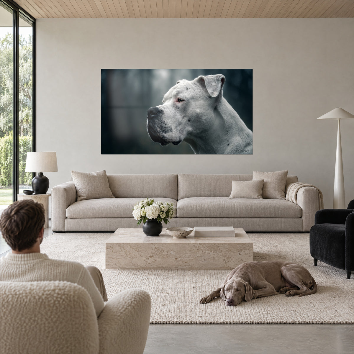 Wall art of a white Dogo Argentino in profile, contemplative gaze against a grey-blue forest backdrop, hung above a sofa in a bright living room