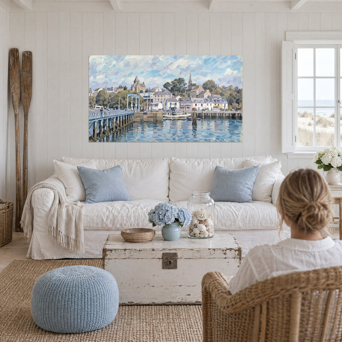 Schilderij van een Bretonse haven met witte gevels en leien daken onder een bewolkte blauwe lucht, metalen steiger, boven een bank in een lichte woonkamer