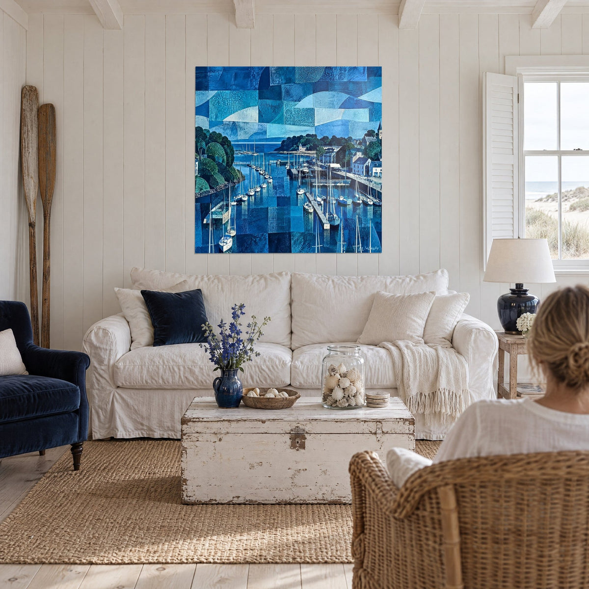 Cuadro puerto bretón en mosaico azul marino y turquesa, veleros amarrados, dos personas de espaldas, sobre un sofá en un salón luminoso