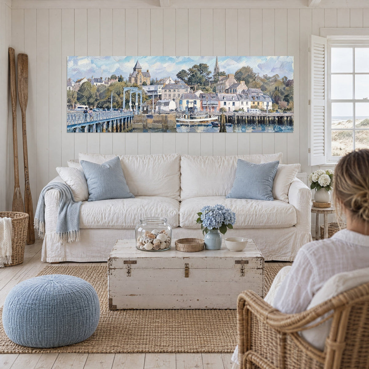 Wall art Breton harbour with white houses and grey bell tower, pale blue sky, above a sofa in a bright living room
