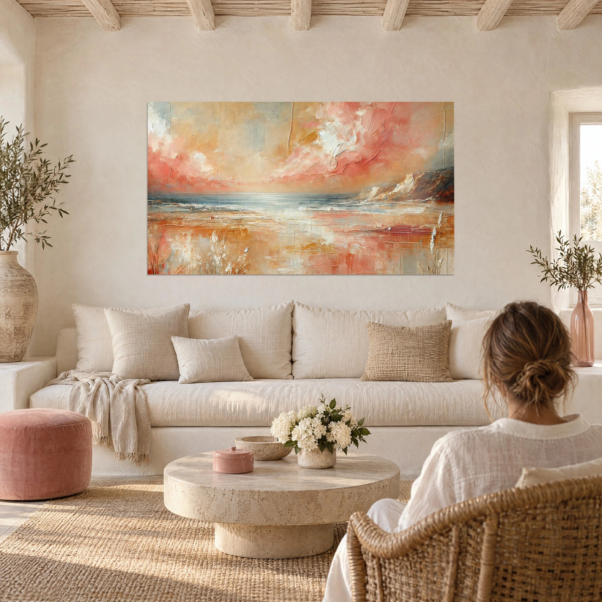 Quadro paesaggio marino astratto con nuvole corallo e ocra, scogliera a destra, donna di spalle sopra un divano in un soggiorno luminoso