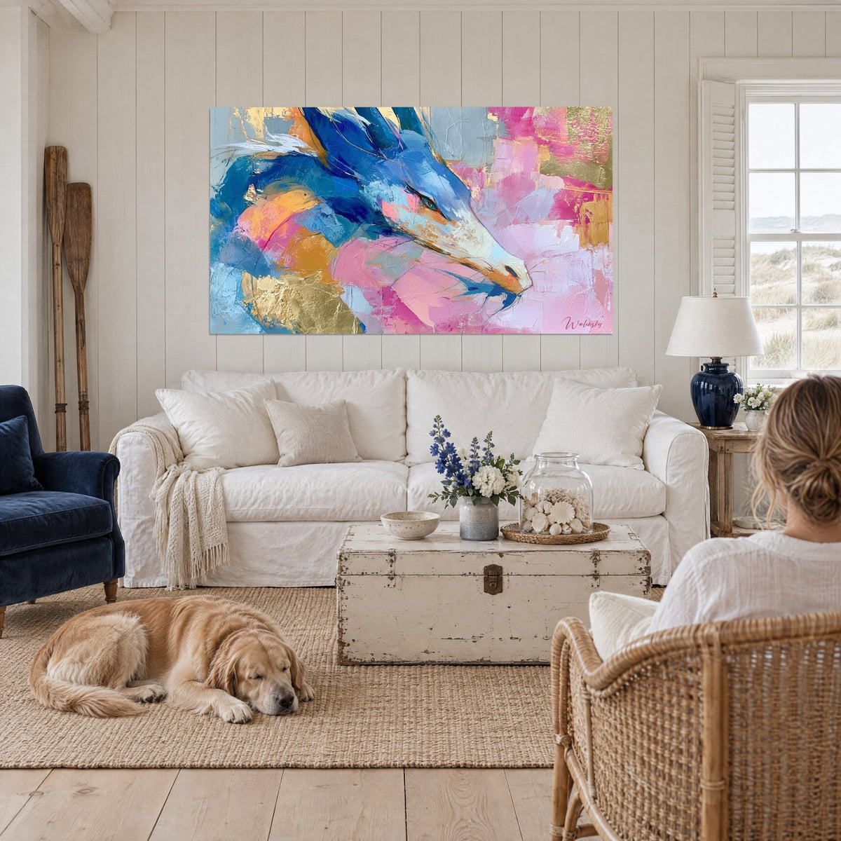 Tableau dragon bleu cobalt au museau blanc, éclats d'or et rose poudré, au-dessus d'un canapé dans un salon lumineux