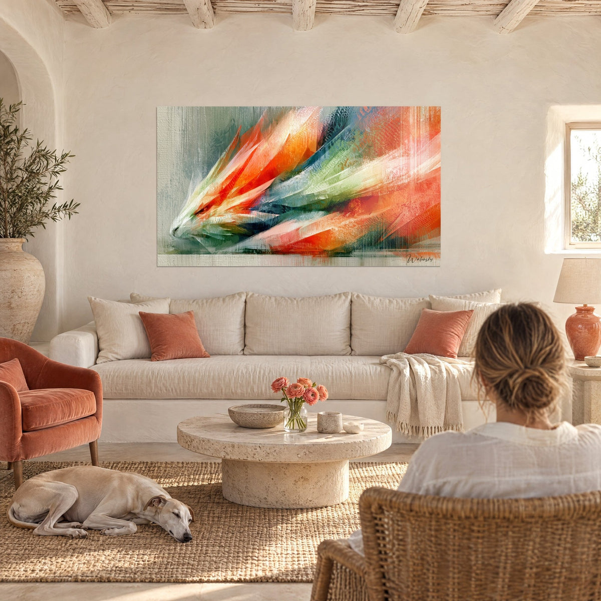 Wall art dragon-bird with sharp orange and green feathers, two people seen from behind, above a sofa in a bright living room