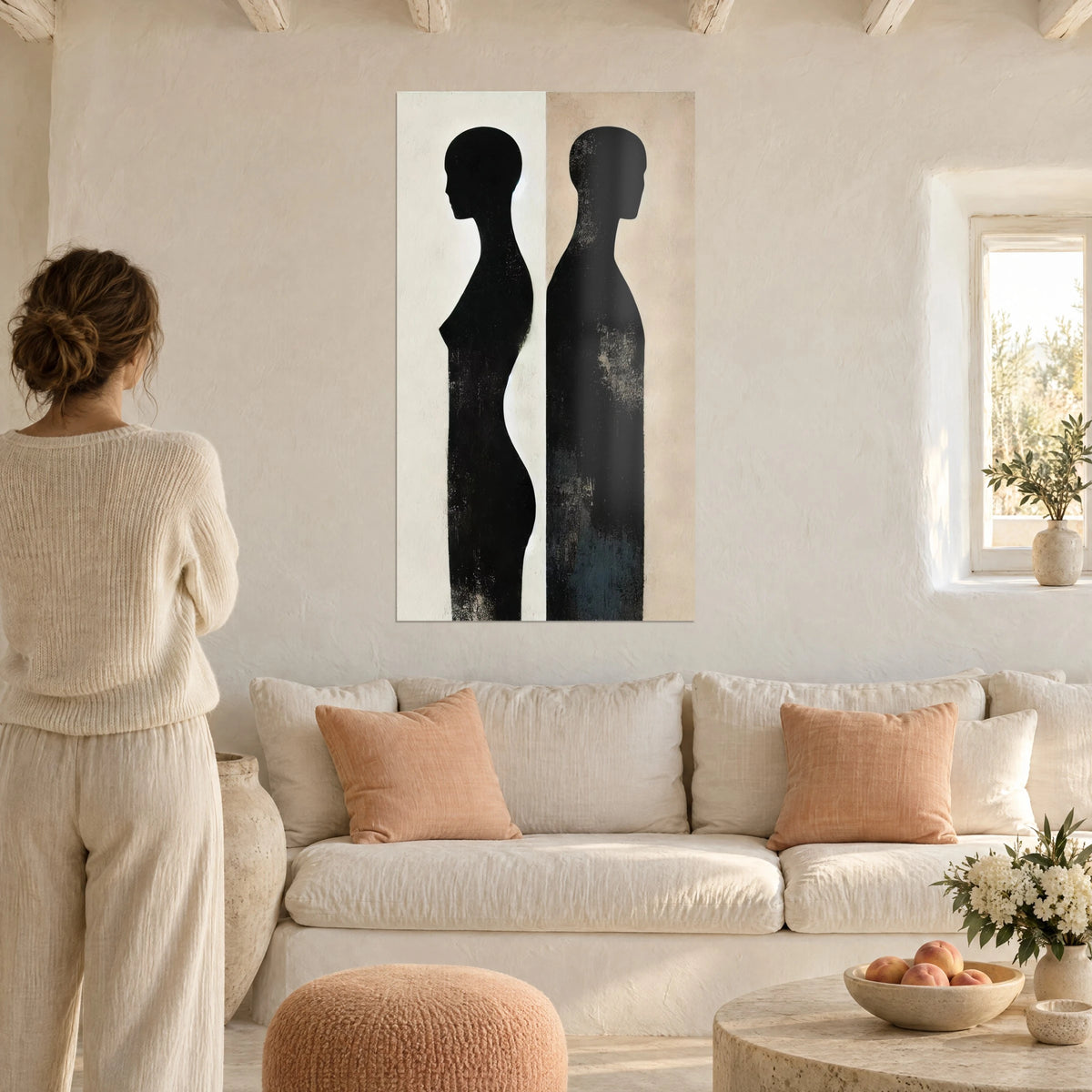 Tableau deux silhouettes noires dos à dos, fond crème et beige rosé, femme de dos, au-dessus d'un canapé dans un salon lumineux