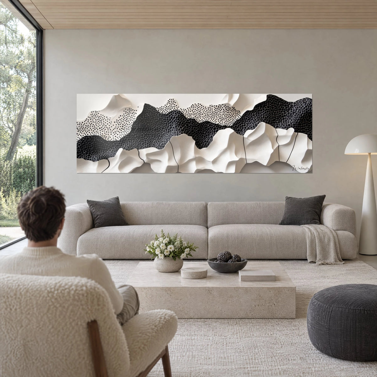 Tableau dunes sculptées ivoire et noir en relief, points noirs en tirets, au-dessus d'un canapé dans un salon lumineux