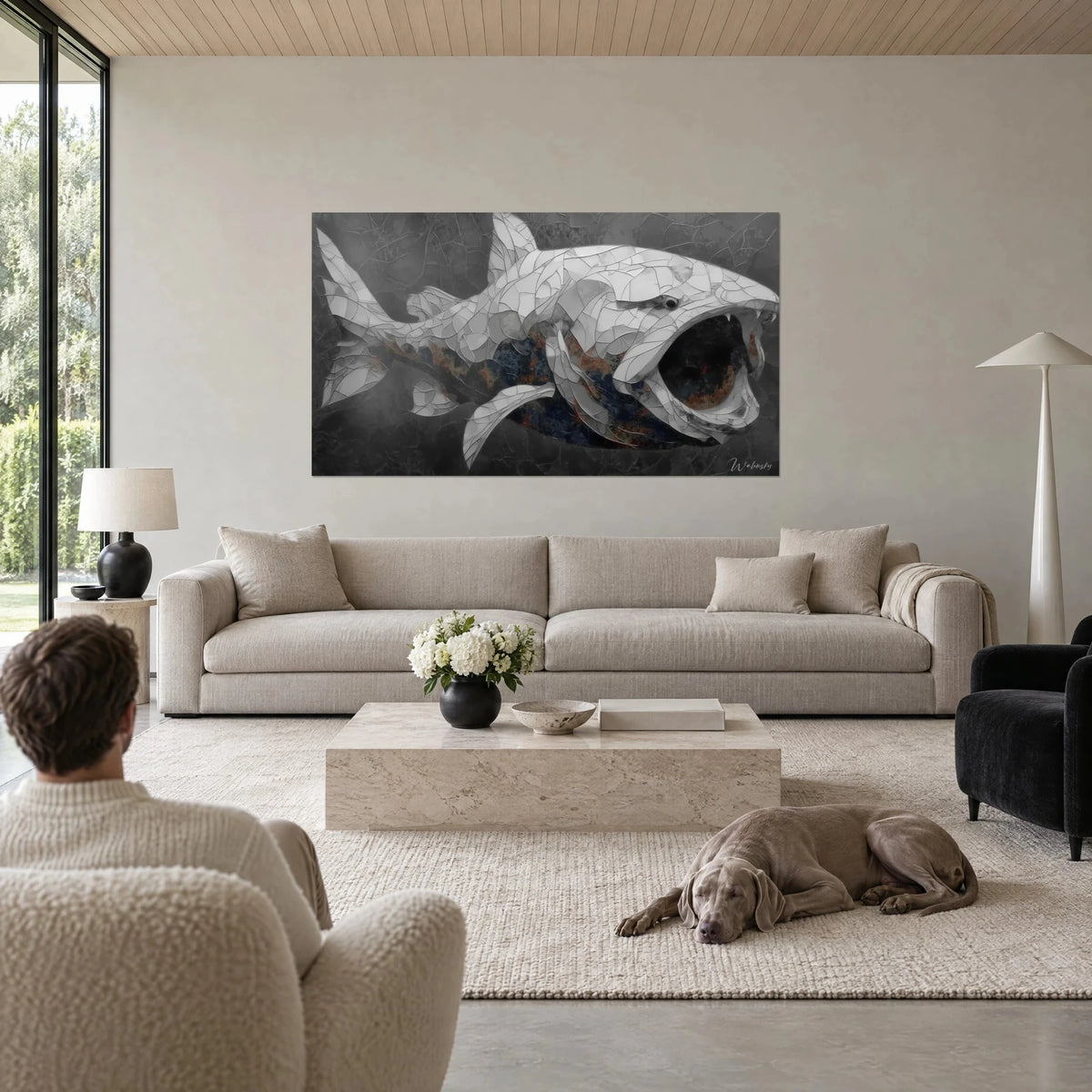 Wall art armored fish in cracked white and grey plates, gaping black jaws, hanging above a sofa in a bright living room