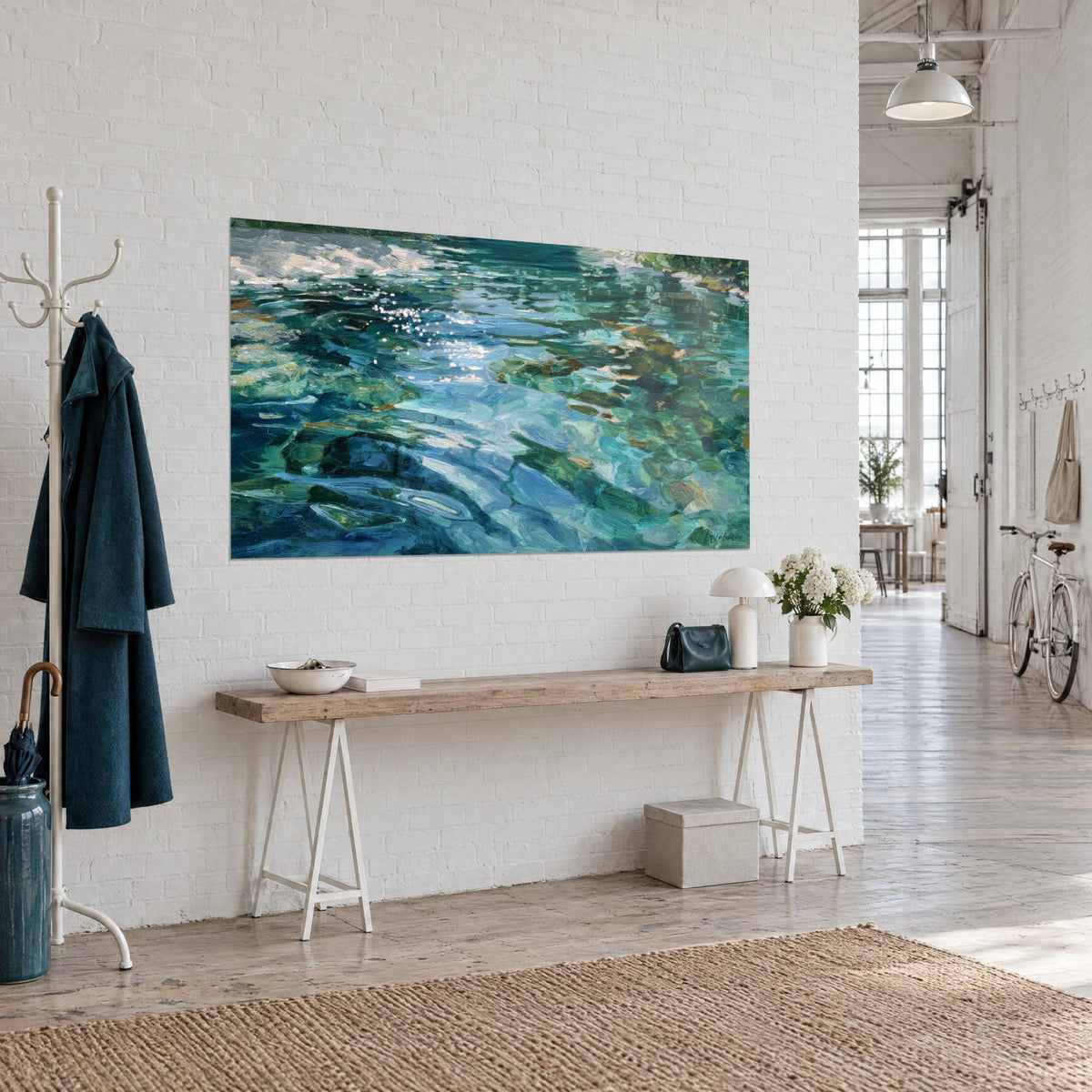 Tableau reflets aquatiques impressionnistes en bleu azur et vert jade, galets ambrés sous la surface, mur de brique blanche, console en bois