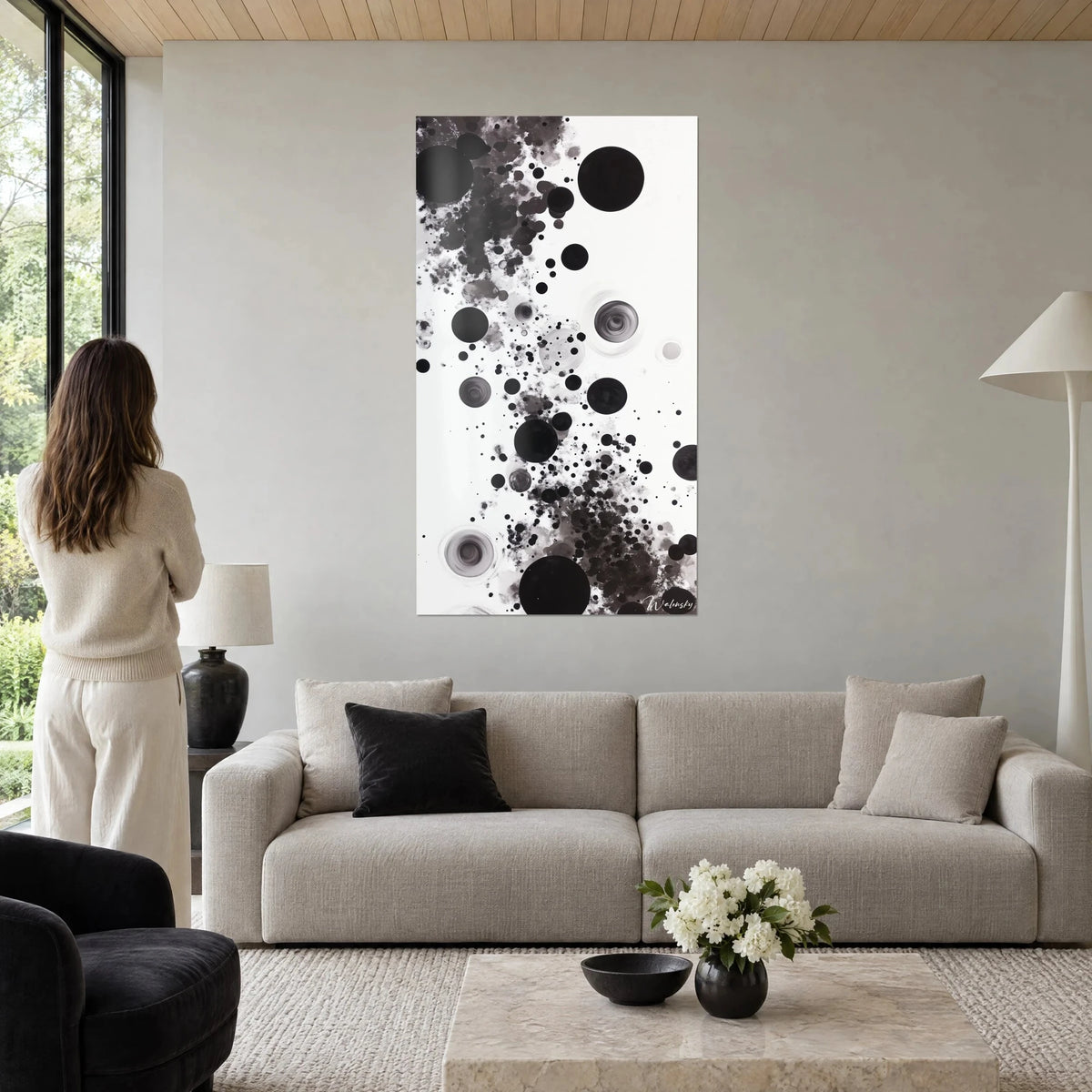 Gemälde mit schwarzen und grauen Tintenklecksen auf weißem Grund, große Scheiben von Spritzern umrandet, über einem Sofa in einem hellen Wohnzimmer