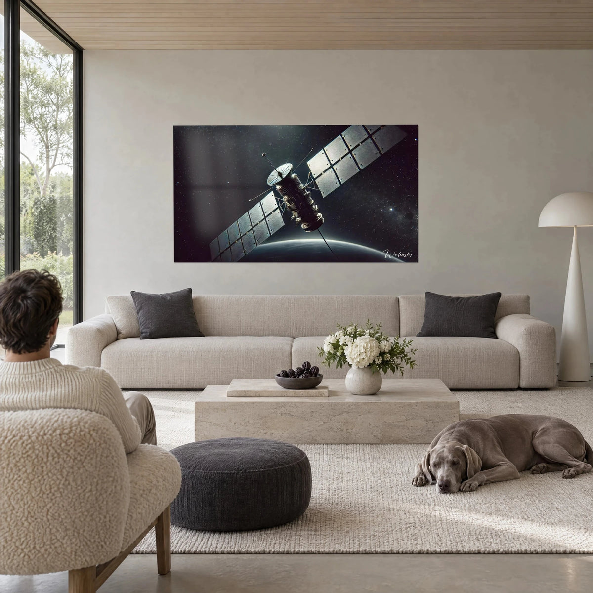 Schilderij observatiesatelliet met zilveren zonnepanelen tegen een zwarte, met sterren bezaaide achtergrond, boven een bank in een lichte woonkamer