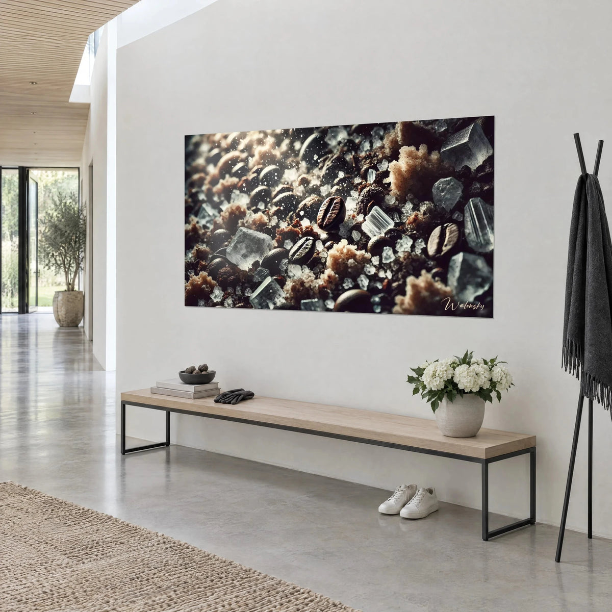 Schilderij met een mozaïek van geroosterde koffiebonen en grof bevroren zout, diepbruin en crèmewit, boven een bank in een lichte gang