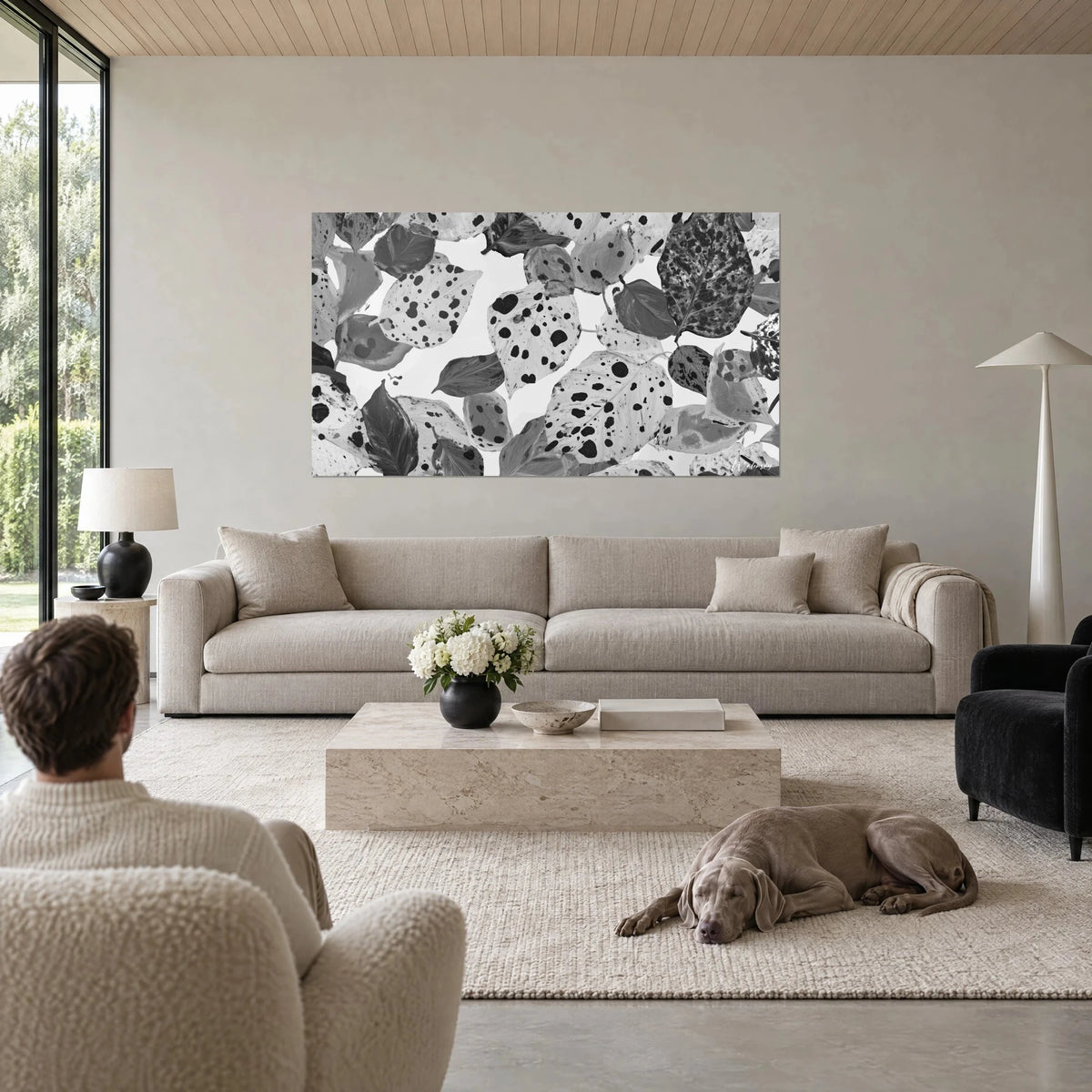 Gemälde gesprenkelte Blätter in Schwarz-Weiß, Tintenflecken auf hellgrauem Grund, über einem Sofa in einem hellen Wohnzimmer