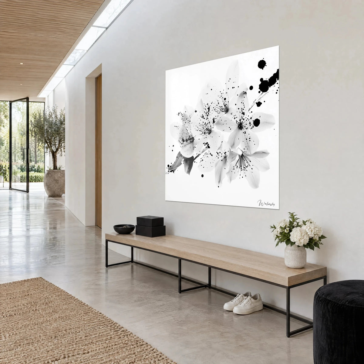 Wall art black and white flowering branch, stamens speckled with ink drops and a large black blot at top right, grey wall, stone hallway