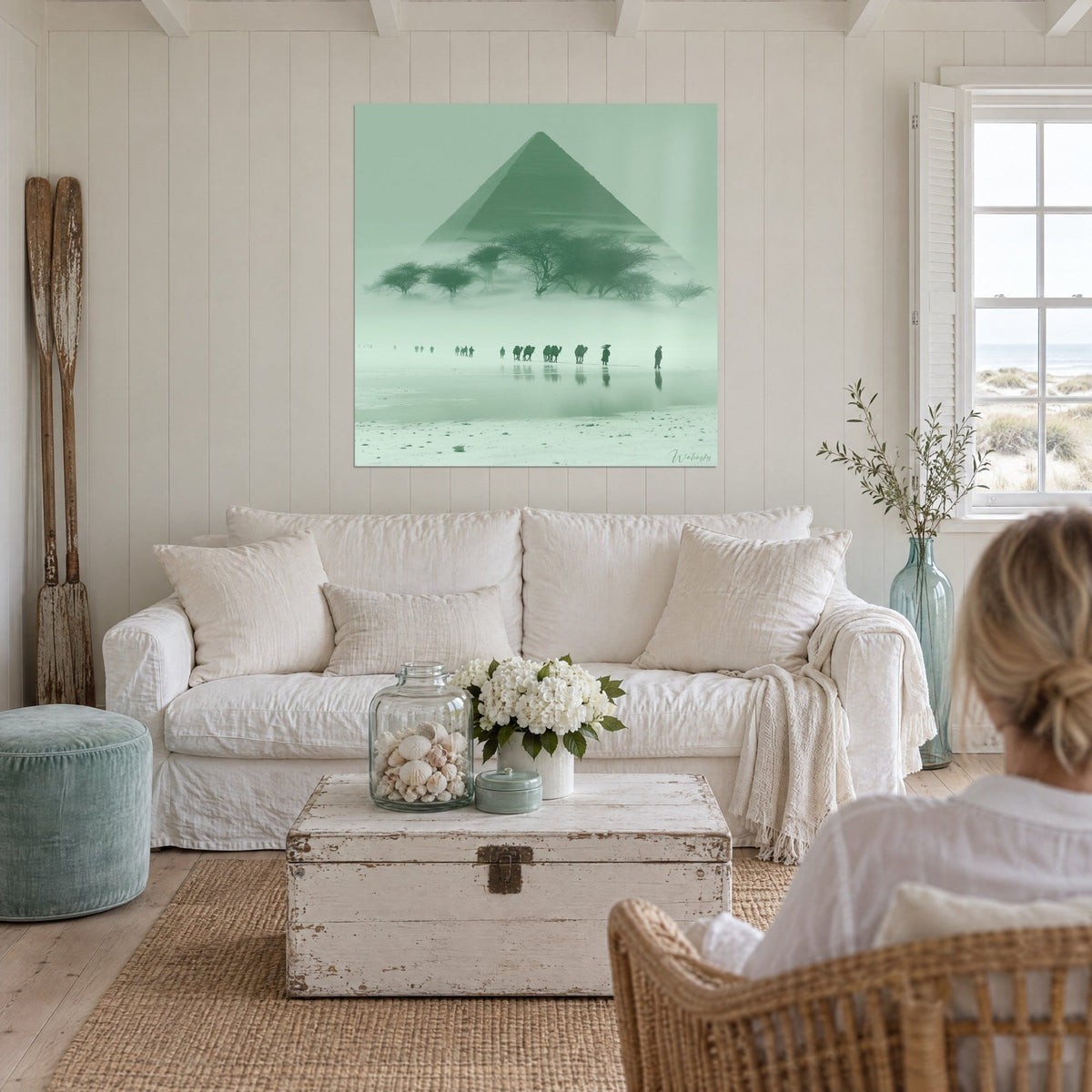 Wall art sage green mist pyramid, acacias and camel caravan reflected, above a sofa in a bright living room