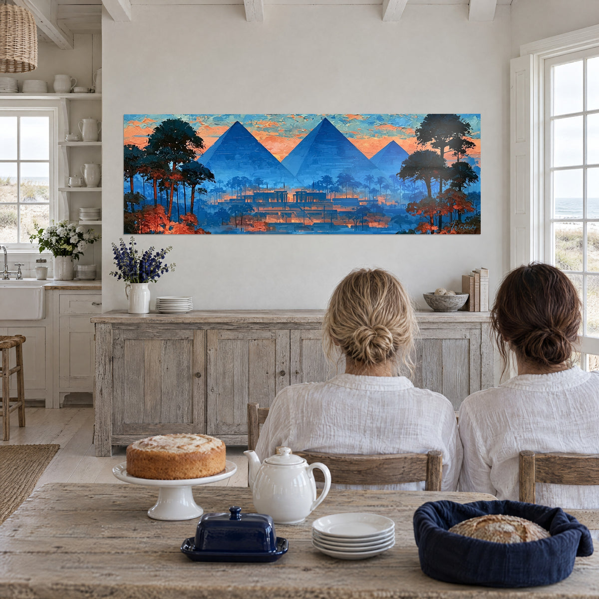 Cuadro de tres tumbas reales azul celeste bajo nubes naranjas y turquesa, dos mujeres de espaldas sentadas a una mesa, sobre un aparador de madera blanqueada