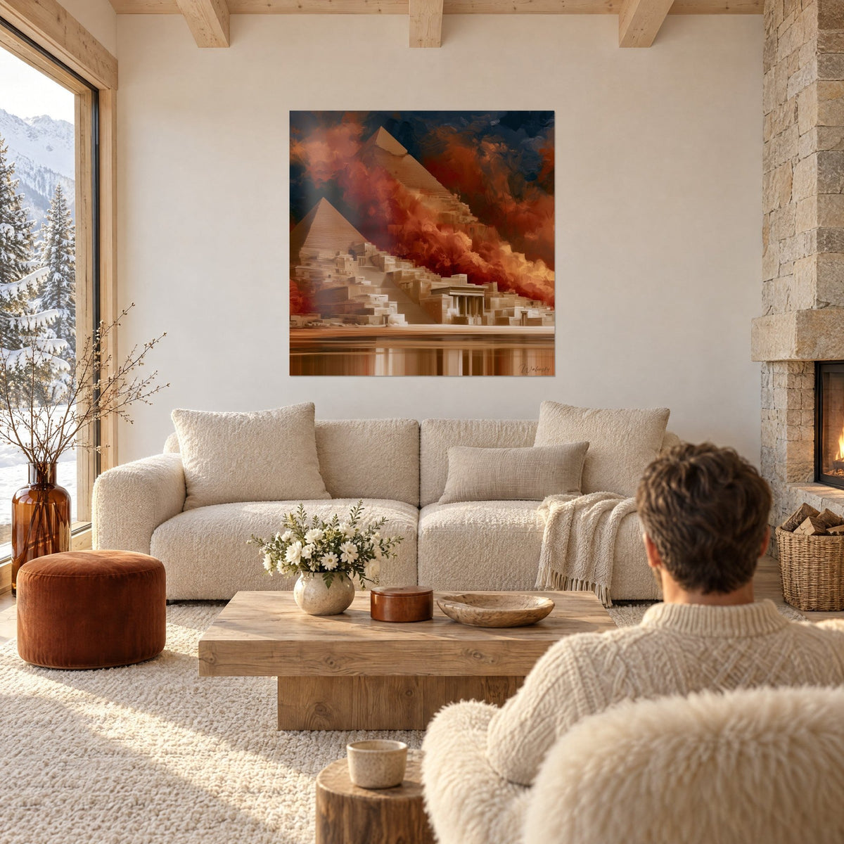 Gemälde Pyramiden in Ocker und ziegelroten Wolkenschwaden vor nachtblauem Himmel, eine Person von hinten, über einem Sofa in einem hellen Wohnzimmer