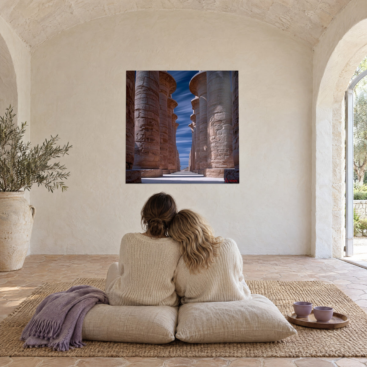 Tableau perspective de colonnes antiques en grès doré, ciel bleu nuit, deux personnes de dos sur des coussins dans un salon voûté